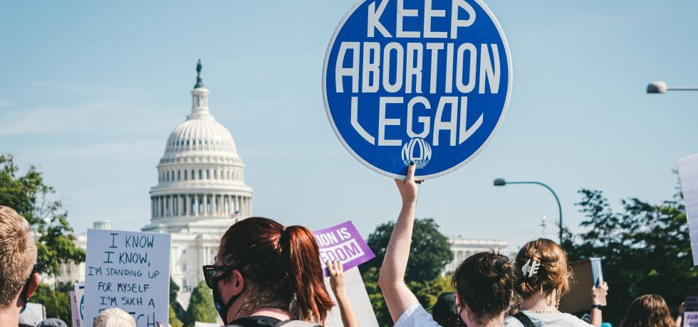 A group of people at a protest in Washington D.C. One person holds a sign which states 'Keep Abortion Legal'.