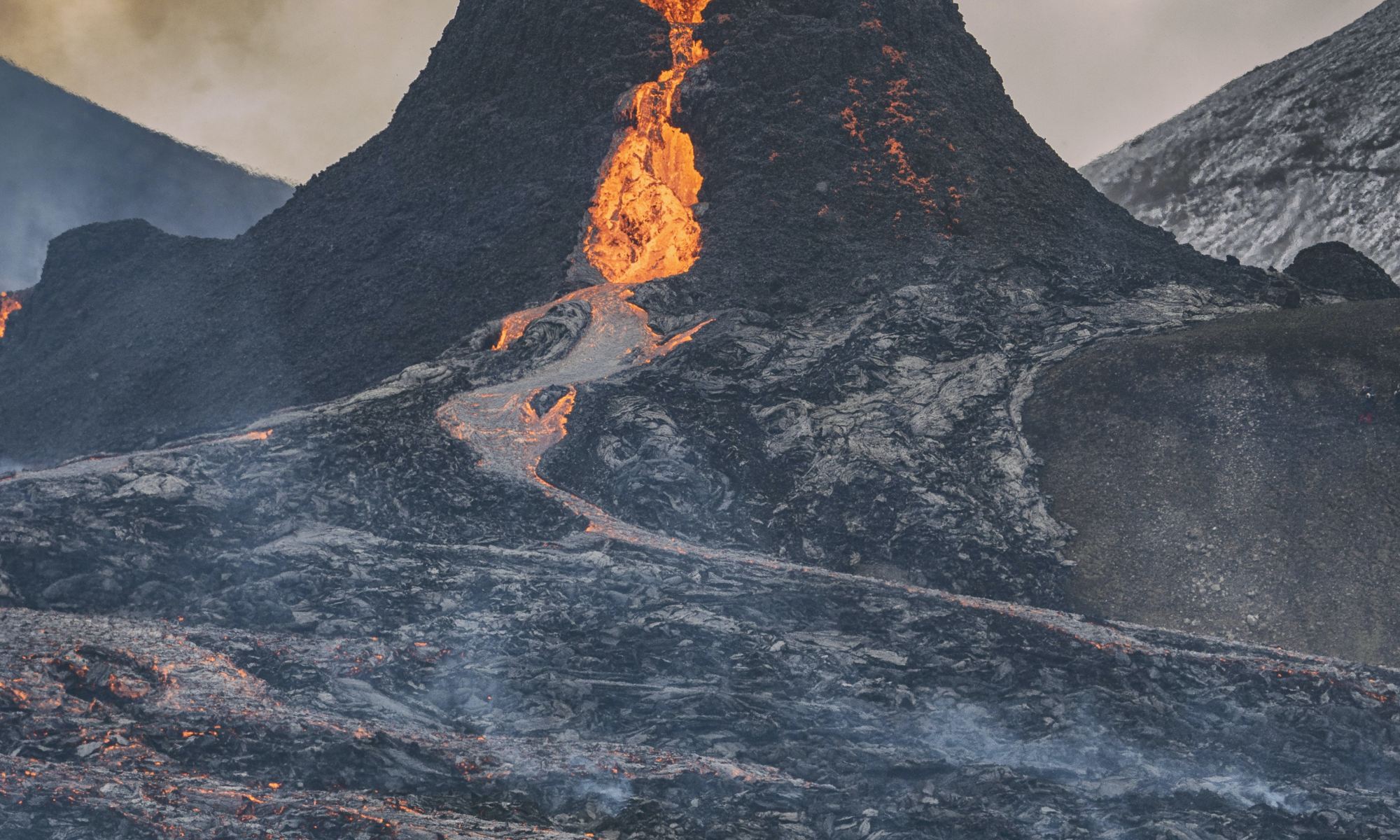 The image shows a person standing in front of Fagradalsfjall volcano, Iceland.