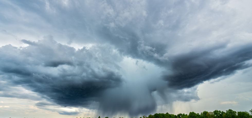 Large storm clouds over a green field.