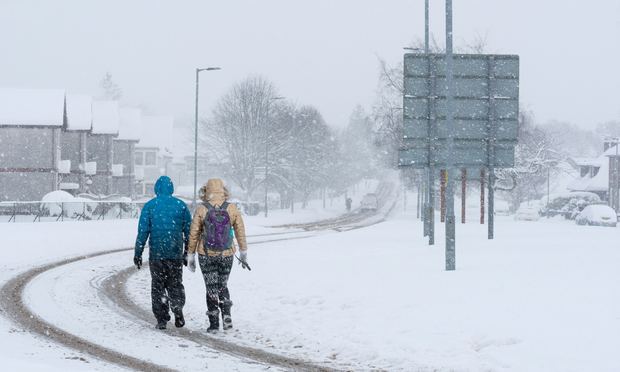 Two people walking on a snowy road.